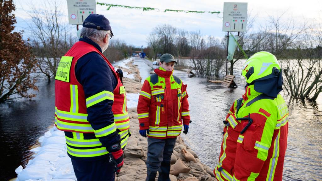 Ehrenamtliche Einsatzkräfte der Feuerwehr besprechen sich in Hodenhagen im deutschen Bundesland Niedersachsen auf der Zufahrt zum Serengeti-Park. Die Hochwasserlage bleibt in vielen Regionen Niedersachsens angespannt.