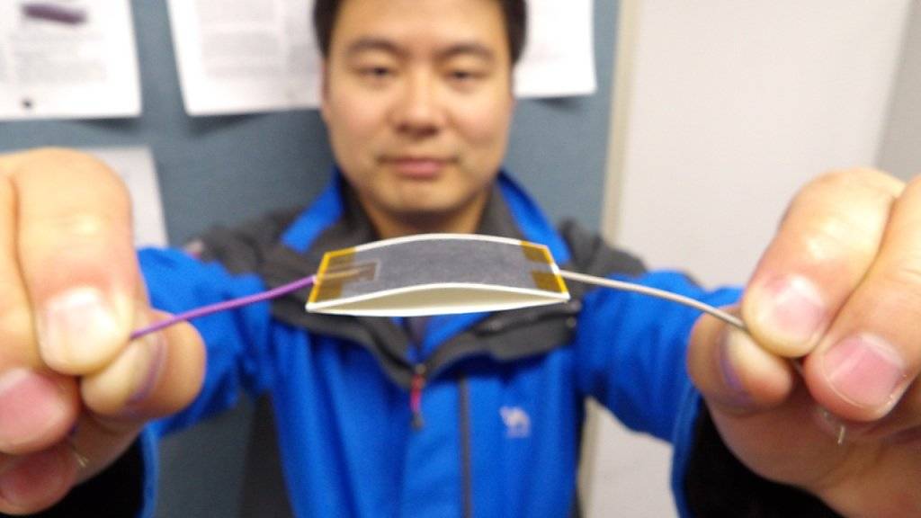 EPFL-Doktorand Xiao-Sheng Zhang mit seinem System: Ein Sandwich aus Graphit-bemaltem Papier und Teflonband erzeugt beim Zusammendrücken ein Ladungsgefälle. Beim Loslassen nimmt das Graphit die Ladung auf und leitet sie ab.