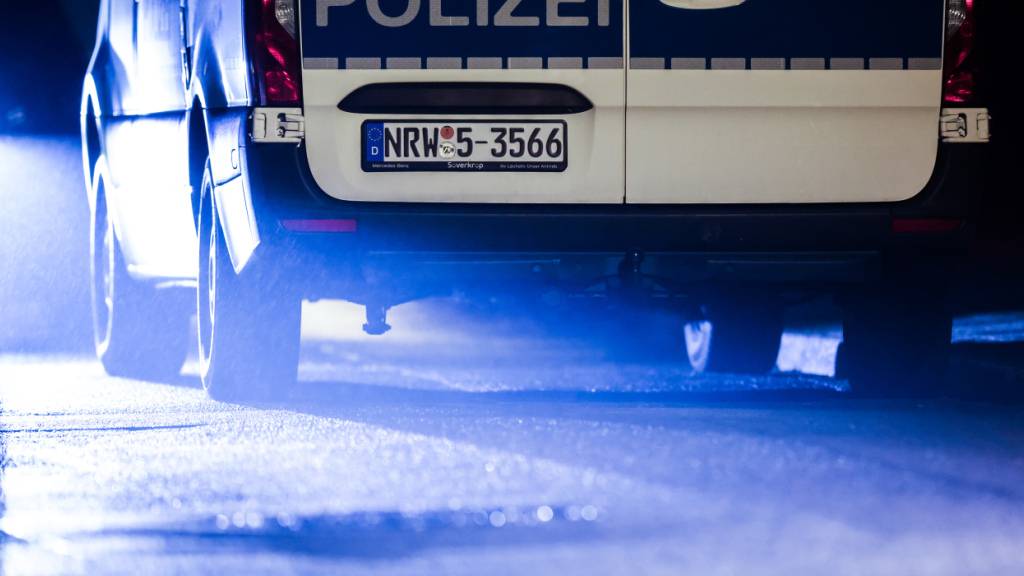 dpatopbilder - Ein Fahrzeug der Polizei steht amTatort am Straßenrand im Scheinwerferlicht eines PKW. Foto: Christoph Reichwein/dpa