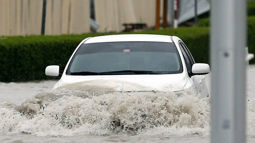 Automobilist pflügt sein Fahrzeug durch die Fluten in den Strassen Dubais