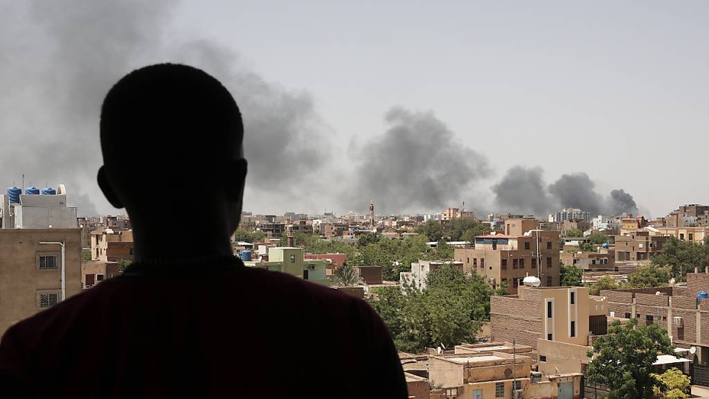 ARCHIV - Ein Mann blickt auf die Hauptstadt Khartum, von der Rauchschwaden aufsteigen. Die paramilitärische Gruppe «Rapid Support Forces» (RSF) hat am Wochenende kurzzeitig die sudanesische Stadt Singa im Südosten des Landes eingenommen. Foto: Marwan Ali/AP/dpa