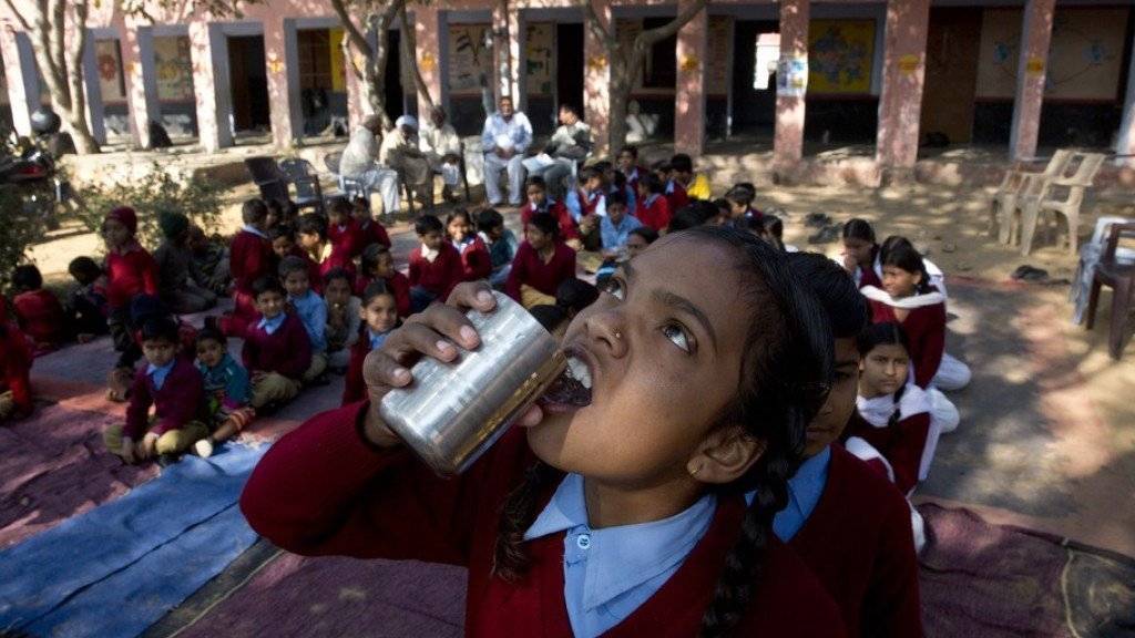Ein Mädchen trinkt im indischen Neemrana Wasser, nachdem es eine Entwurmungspille gekaut hat. Die Würmer leben vorzugsweise im Darm und können die körperliche und geistige Entwicklung stören