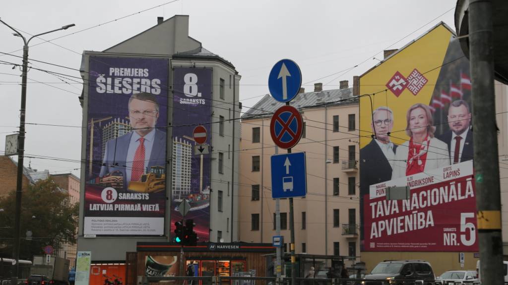 Riesige Wahlplakate der populistischen Oppositionspartei «Lettland an erster Stelle» (l) und der mitregierenden nationalkonservativen «Nationalen Allianz» hängen an Hauswänden in der Hauptstadt Riga. Foto: Alexander Welscher/dpa/Archivbild