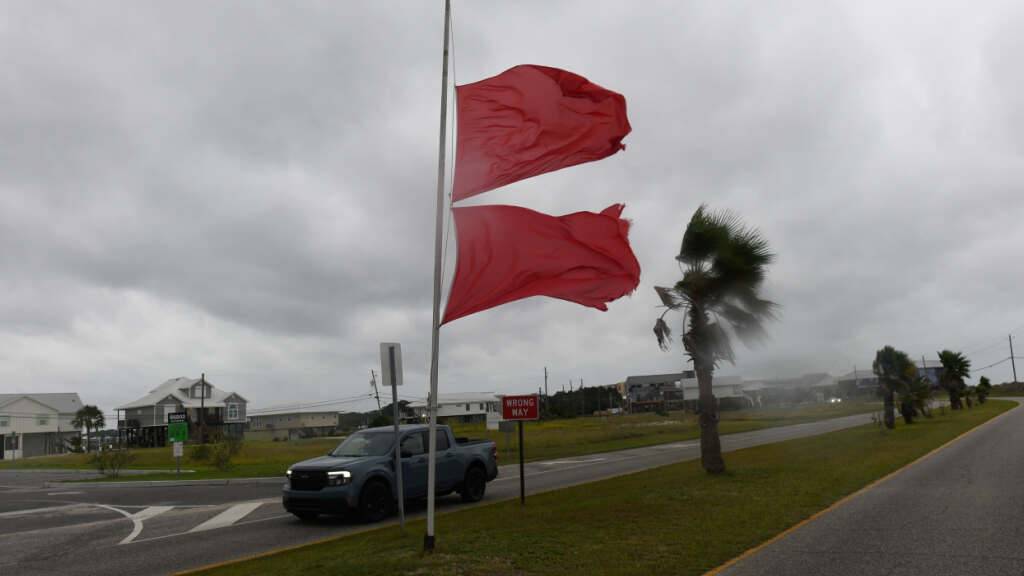 Marineflaggen wehen im Wind, der durch den Sturm «Isaias» verursacht wird, während ein Fahrzeug vorbeifährt. Foto: Octavio Jones/AP/dpa