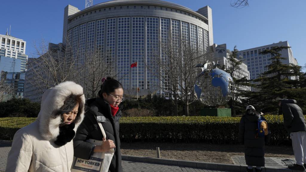 ARCHIV - Menschen gehen am chinesischen Außenministerium in Peking vorbei. Foto: Andy Wong/AP/dpa/Archivbild