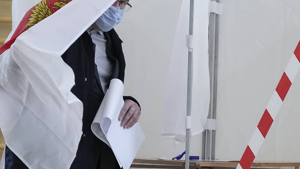 Ein Mann bereitet sich auf die Stimmabgabe in einem Wahllokal in Russland vor. Foto: Pavel Golovkin/AP/dpa