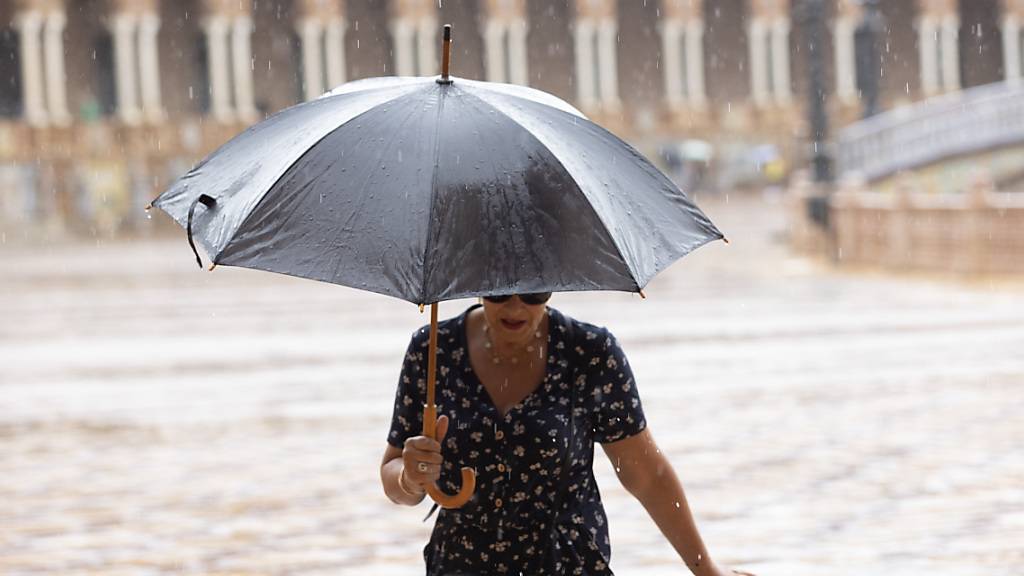 Eine Fuflg‰ngerin sch ̧tzt sich mit einem Regenschirm vor dem Regen in Sevilla. Die Behˆrden haben f ̧r die n‰chsten Tage landesweit auflergewˆhnlich heftige Regenf‰lle angek ̧ndigt. Foto: RocÌo Ruz/EUROPA PRESS/dpa