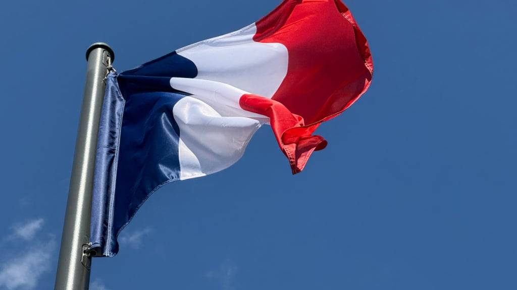 ARCHIV - Die Frankreich-Flagge, auch Trikolore genannt, weht in der Pariser Innenstadt vor blauem Himmel. Foto: Rachel Sommer/dpa