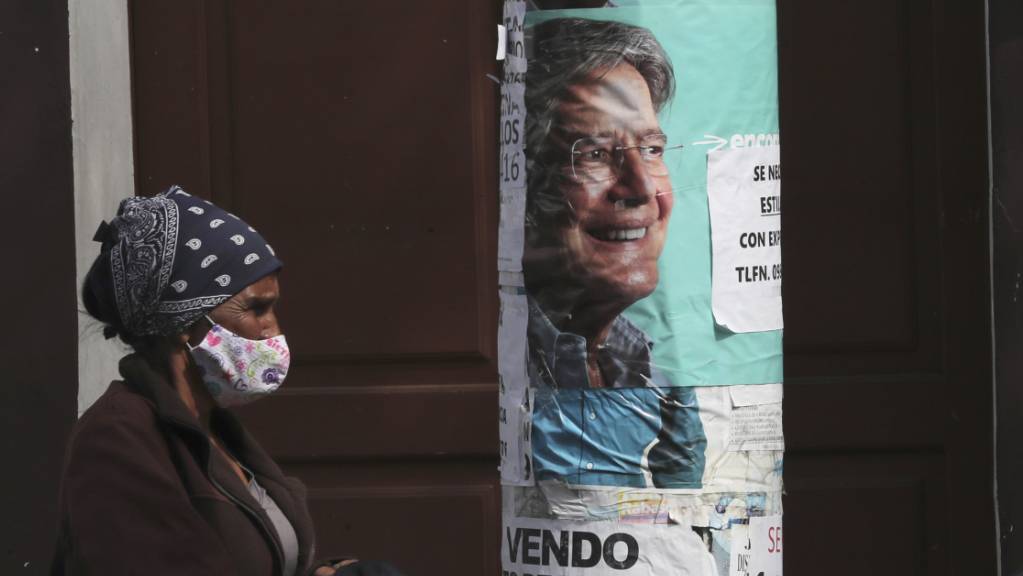 Eine Frau geht an einem Wahlplakat des Präsidentschaftskandidaten Lasso vorbei. Foto: Dolores Ochoa/AP/dpa