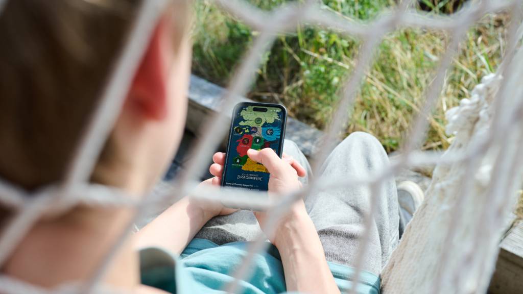 ILLUSTRATION - Ein Teenager liegt in einem Hängesessel und guckt auf sein Handy. (gestellte Szene) Foto: Annette Riedl/dpa