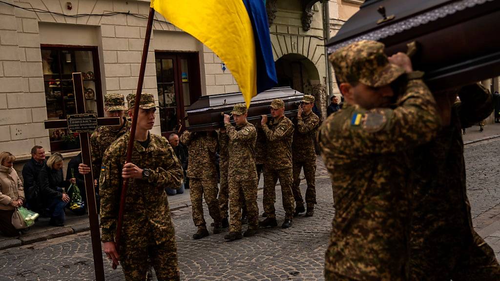 ARCHIV - Soldaten tragen die Särge von zwei ukrainischen Armeeoffizieren während der Zeremonie zu ihrer Beerdigung. Foto: Francisco Seco/AP/dpa