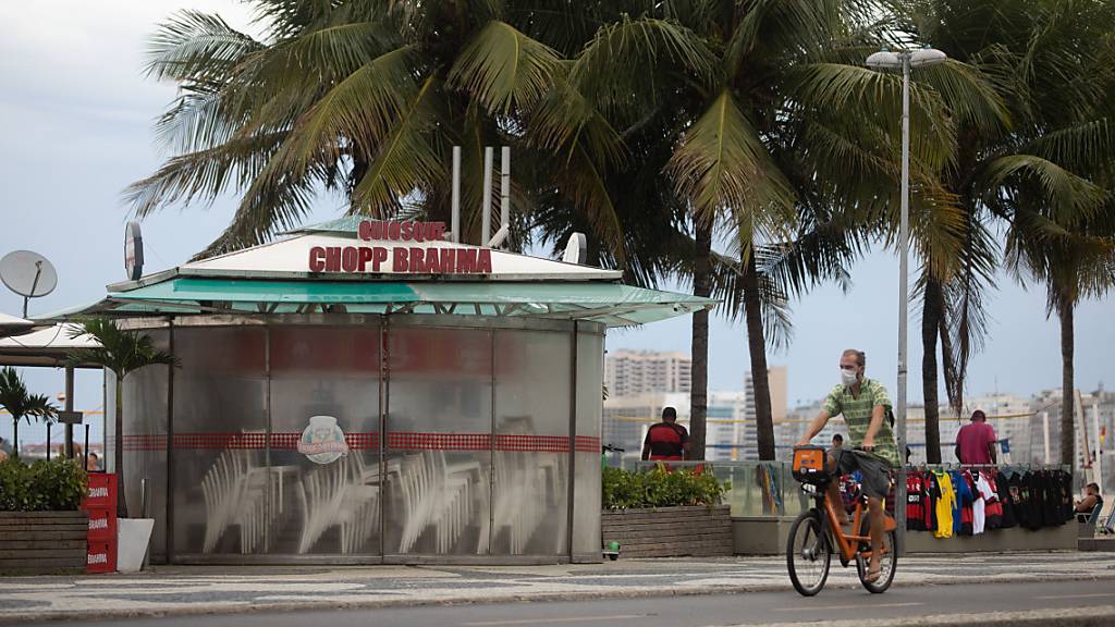 Ein Mann fährt mit dem Rad an einem geschlossenen Kiosk am brasilianischen Strand Copacabana vorbei. (Archivbild)