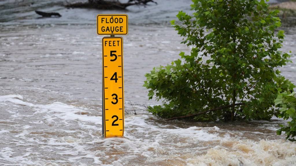 Ein Pegelmesser zeigt die Höhe des Wassers an, das über einer Landstraße in der Nähe von Kerrville fließt. Foto: Eric Gay/AP/dpa
