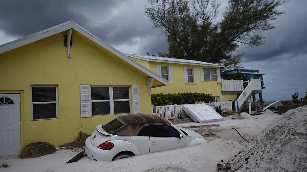 Ein Auto liegt nach Hurrikan «Helene» halb vergraben im Sand am Bradenton Beach, während sich Hurrikan «Milton» Anna Maria Island nähert. Foto: Rebecca Blackwell/AP/dpa