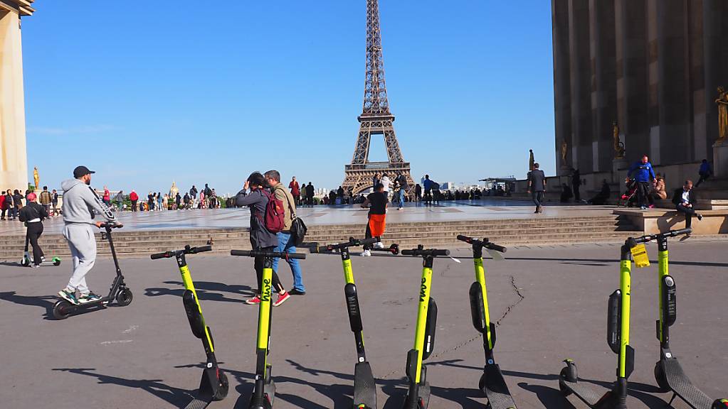 E-Tretroller stehen zum Mieten auf der Place du Trocadero bereit – im Hintergrund ist der Eiffelturm zu sehen. Das Tempo von E-Scootern wird in Paris von den drei großen Vermietern seit Montag in Teilen des Zentrums auf Tempo 10 gedrosselt.
