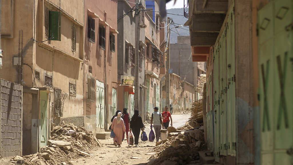 Menschen tragen einige ihrer Habseligkeiten, während sie die durch das Erdbeben beschädigte Stadt Amizmiz in der Nähe von Marrakesch verlassen. Trotz diplomatischer Spannungen hat Algerien in Folge des schweren Erdbebens in Marokko angekündigt, Rettungsteams in das Nachbarland zu senden. Foto: Mosa'ab Elshamy/AP/dpa