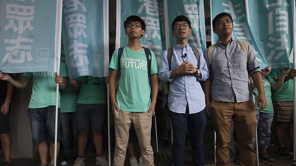 Die Studenten Joshua Wong (links), Nathan Law (Mitte) und Alex Chow (rechts) vor dem Gericht in Hongkong, das sie wegen ihrer Rolle bei der «Regenschirm-Revolution» zu Sozialdienst und einer Bewährungsstrafe verurteilte.