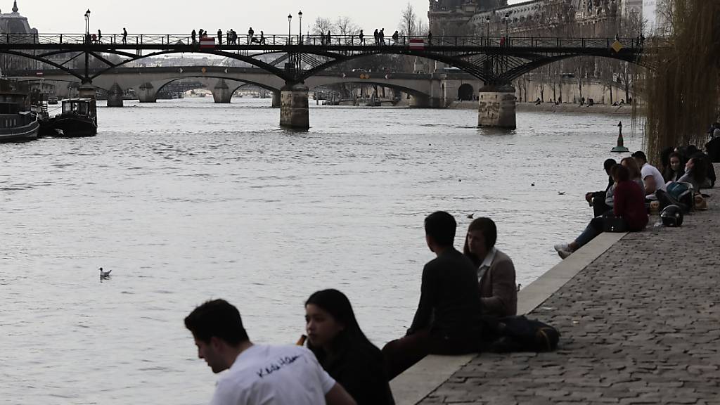 Menschen am Ufer der Seine in Paris. Foto: Lewis Joly/AP/dpa