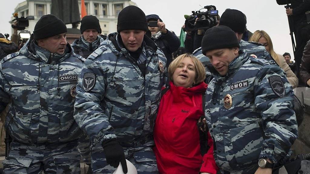 Polizisten in Moskau nehmen eine Frau fest, die mit einem Plakat gegen den Einsatz in Syrien protestierte.
