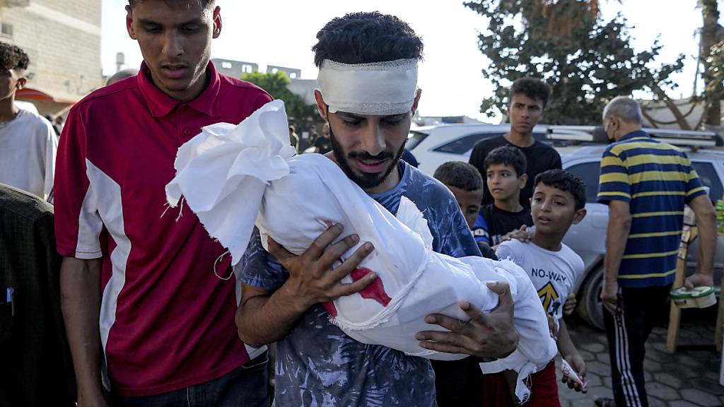 ARCHIV - Ein Angehöriger hält die Leiche eines Kindes, das bei der israelischen Bombardierung des Gazastreifens getötet wurde, in einer Leichenhalle des Krankenhauses in Deir al-Balah. Foto: Abdel Kareem Hana/AP/dpa