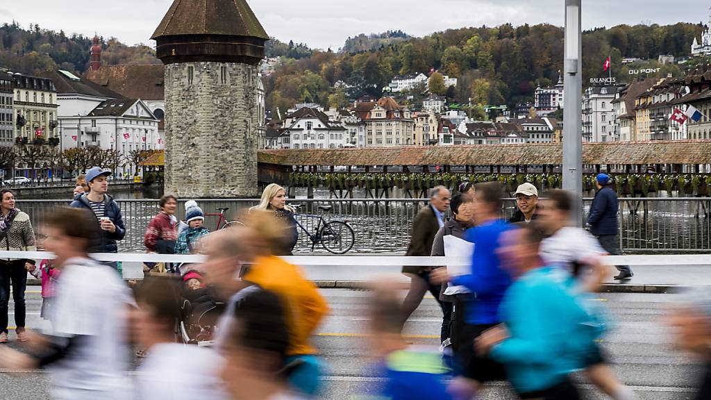 Läuferinnen und Läufer rennen während des Swiss City Marathons über die Seebrücke mit der Kapellbrücke im Hintergrund. (Archivaufnahme)