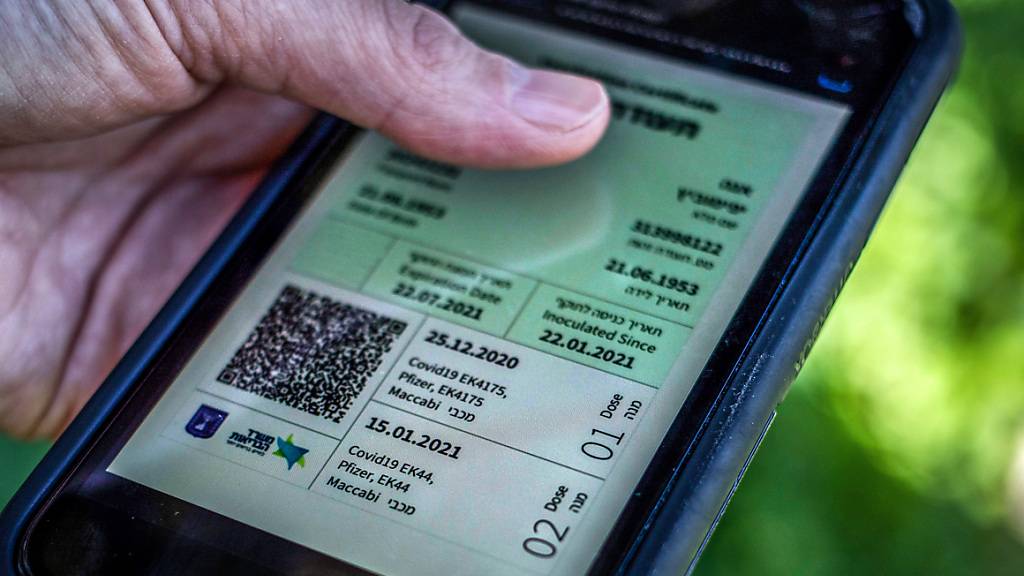 ARCHIV - Ein Mann hält ein Smartphone in der Hand, auf dem der sogenannte «Grüne Pass» abgebildet ist. Wegen steigender Corona-Infektionszahlen gilt in Israel seit Donnerstag wieder der sogenannte Grüne Pass. Foto: Ilia Yefimovich/dpa