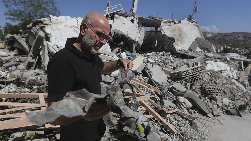 Ein Mann zeigt die Überreste einer Rakete eines israelischen Kampfflugzeugs, die in ein Haus einschlug und einen Hisbollah-Kämpfer und zwei seiner zivilen Familienmitglieder tötete. Foto: Mohammad Zaatari/AP/dpa