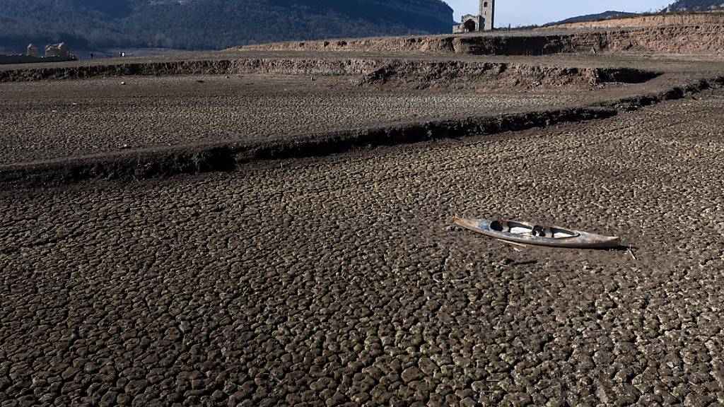 ARCHIV - Ein verlassenes Kanu liegt auf dem rissigen Boden des Sau-Stausees etwa 100 Kilometer nördlich von Barcelona. Die nordöstliche Region in Katalonien ist schwer von der Trockenheit betroffen. Foto: Emilio Morenatti/AP/dpa