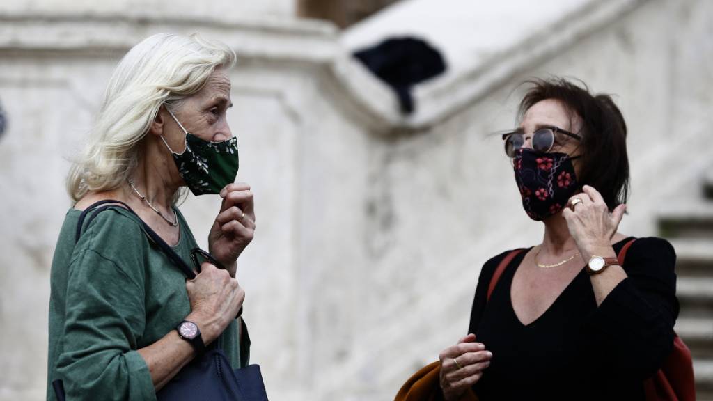Menschen mit Mund-Nasen-Schutz stehen vor einer Treppe in Rom.