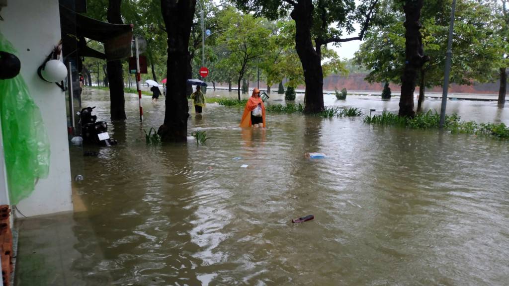 Passanten waten durch eine überflutete Strasse. Nach Rekordregenfällen in Vietnam stehen viele Straßen unter Wasser, vor allem in der historischen Stadt Hue. Foto: Hoang Le Y Minh/dpa