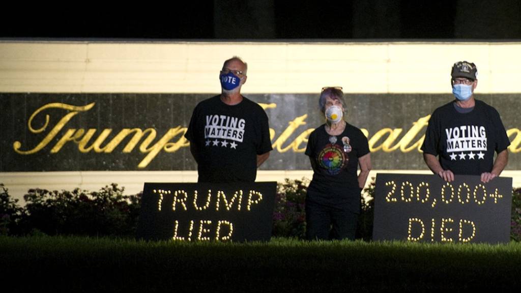 Die Demonstranten Mark Beaumont (l-r), Joyce Brown und Bruce Brown halten in der Nähe des Trump International Golf Club eine Mahnwache ab. In den USA sind inzwischen über 200 000 Menschen nach einer Corona-Infektion gestorben. Foto: Meghan Mccarthy/Palm Beach Post via ZUMA Wire/dpa