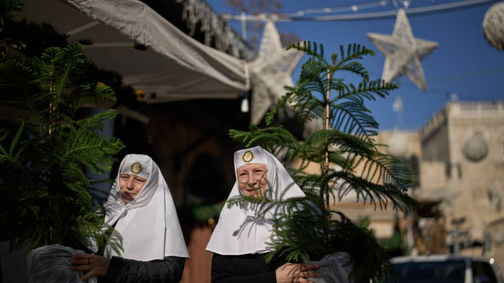 ARCHIV - Orthodoxe Christinnen tragen ihre Weihnachtsbäume vor dem Weihnachtsfest nach Hause. Foto: Leo Correa/AP/dpa