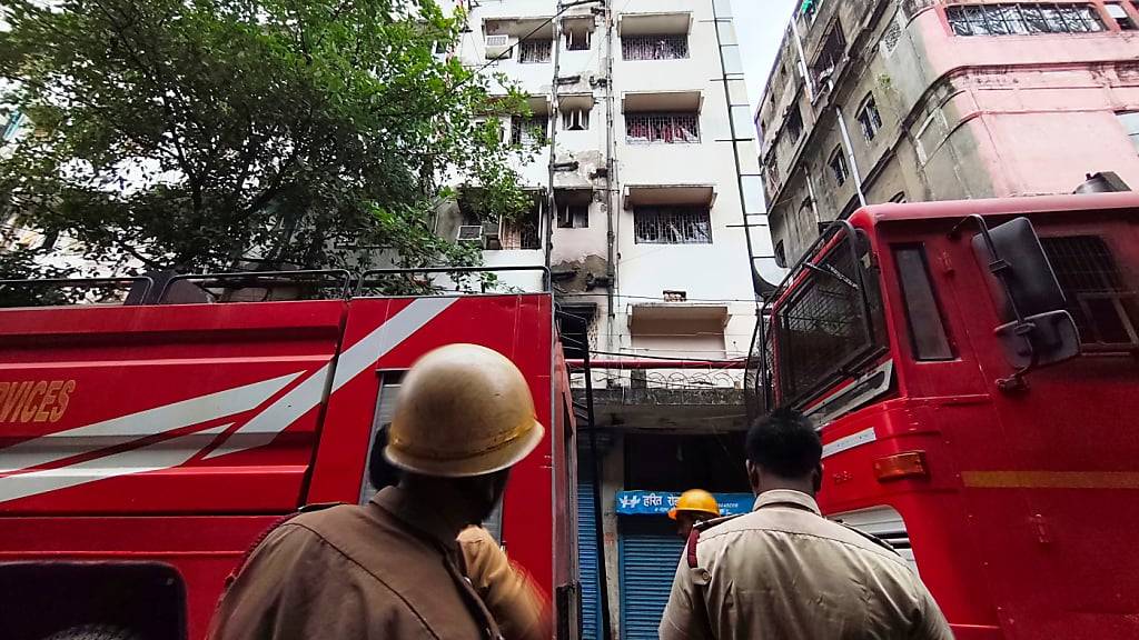 Feuerwehrleute stehen vor einem Hotelgebäude, das in Brand geraten ist. Bei einem Brand in einem Hotel in der ostindischen Millionenstadt Kolkata sind mindestens 14 Menschen ums Leben gekommen. Foto: Bikas Das/AP/dpa