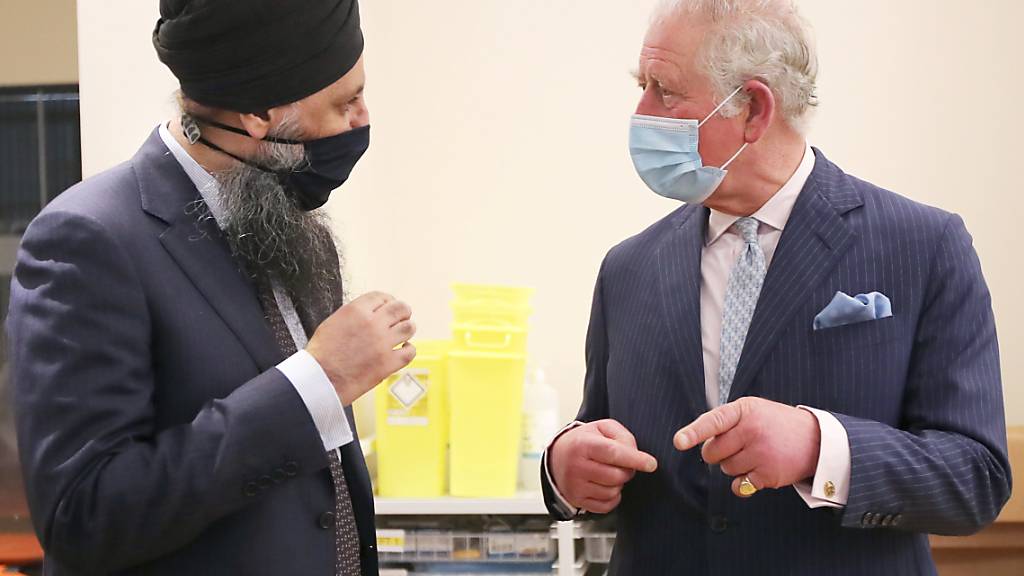 Der britische Prinz Charles (r), Prinz von Wales, unterhält sich mit Inderjit Singh, Chefapotheker, im Rahmen seines Besuchs im Queen Elizabeth Krankenhaus. Das Königspaar möchte sich bei den Freiwilligen bedanken, die an einer klinischen Studie für die Impfungen gegen das Coronavirus teilnehmen. Foto: Molly Darlington/PA Wire/dpa