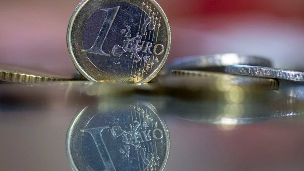 ARCHIV - Eine 1-Euro-Münze steht auf einem Tisch, umgeben von anderen Euro-Münzen. Foto: Hendrik Schmidt/dpa