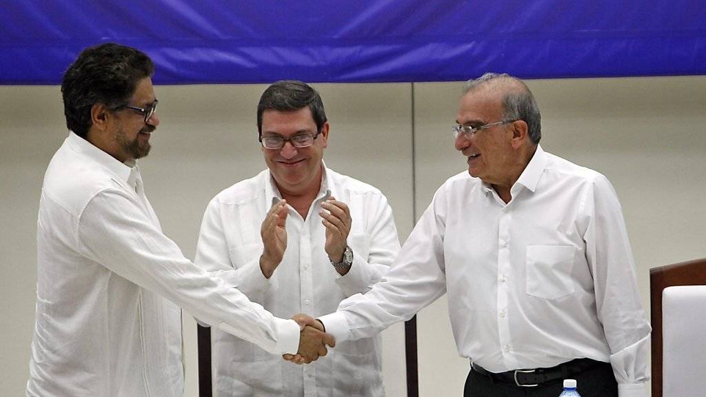 Die Chefs der beiden Verhandlungsdelegationen schütteln sich im Beisein des kubanischen Aussenministers Bruno Rodriguez nach ihrer Einigung über ein Friedensabkommen die Hände. Kolumbiens Regierung und die FARC-Rebellen verhandelten fast vier Jahre lang.