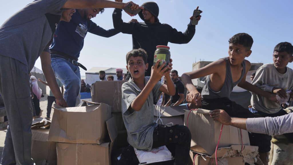 dpatopbilder - Palästinenser tragen in Rafah im südlichen Gazastreifen Kisten mit Lebensmitteln und humanitären Hilfspaketen. Foto: Abdel Kareem Hana/AP/dpa