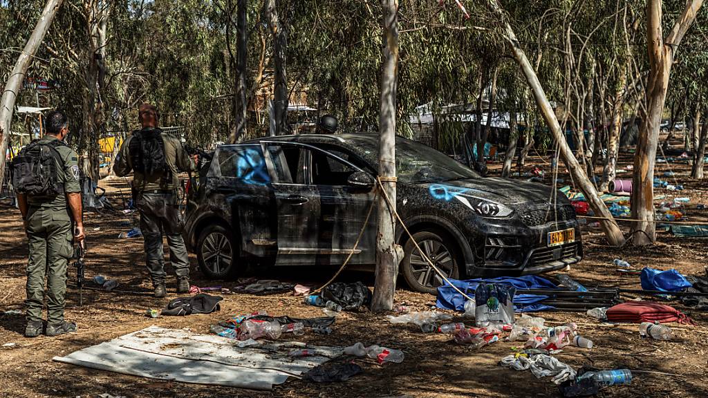 Israelische Soldaten stehen neben einem verlassenen Auto auf dem Gelände des Supernova-Wüstenmusikfestivals. Angreifer der im Gazastreifen herrschenden Islamistenorganisation Hamas hatten Hunderte Menschen auf dem Festival getötet und viele weitere als Geiseln verschleppt. Foto: Ilia Yefimovich/dpa