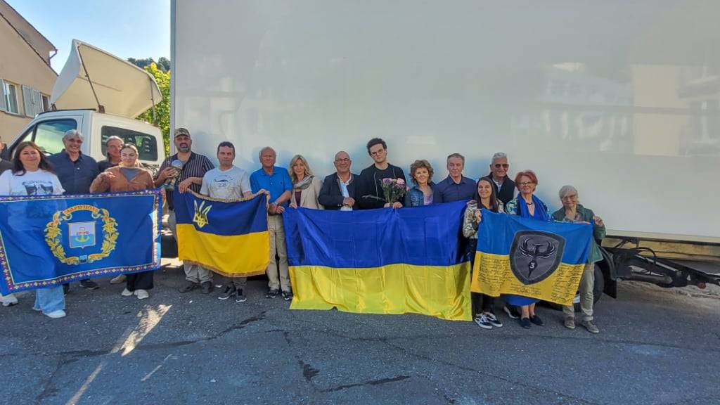 Vertreterinnen und Vertreter mehrerer ukrainischer Hilfsorganisationen, weiterer Unterstützer sowie Verkäufer und Fahrer bei der Übergabe des Transporters.