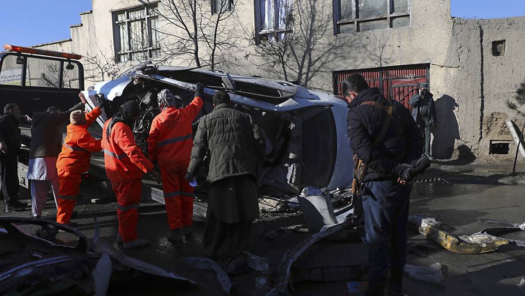 Afghanische Sicherheitskräfte und Gemeindearbeiter entfernen ein beschädigtes Fahrzeug nach einem Bombenanschlag. Bei einem erneuten Anschlag in der afghanischen Hauptstadt Kabul sind mindestens fünf Menschen getötet worden, vier von ihnen Ärzte. Foto: Rahmat Gul/AP/dpa