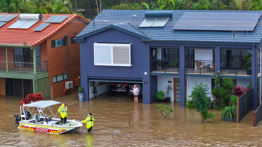 dpatopbilder - Eine Luftaufnahme zeigt Mitarbeiter der NSW Fire Rescue, die einem älteren Bewohner während der Überschwemmungen helfen. An der Ostküste Australiens sind nach heftigen Regenfällen ganze Ortschaften überflutet und teilweise von der Außenwelt abgeschnitten. Foto: Lindsay Moller/AAP/dpa