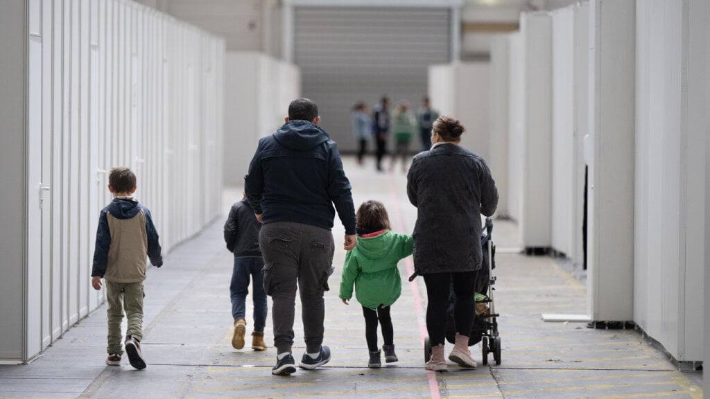 ARCHIV - Eine Flüchtlingsfamilie geht durch die zu einer Massenunterkunft umfunktionierten Messehalle in Frankfurt. Foto: Boris Roessler/dpa