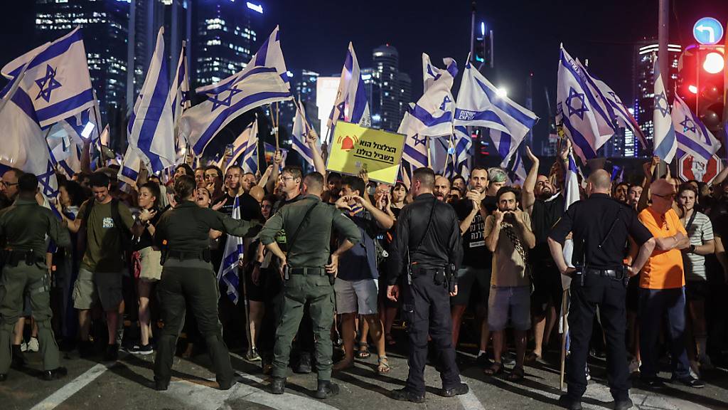 Polizisten stehen vor Demonstranten während eines Protests in Tel Aviv gegen die israelische Regierung. Foto: Ilia Yefimovich/dpa