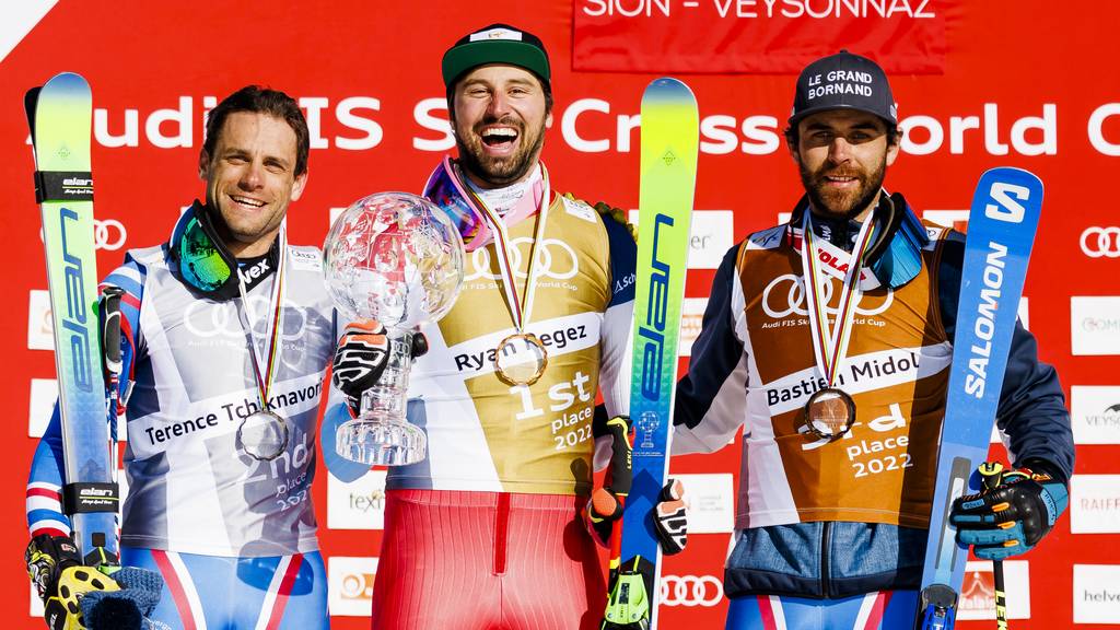 Second placed Terence Tchiknavorian of France, left, winner Ryan Regez of Switzerland, center, and third placed Bastien Midol of France, right, celebrate men's overall crystal globe trophy on the podium during the men's Ski Cross event at the FIS Ski Cross, SX, World Cup Finals, in Veysonnaz, Switzerland, Saturday, March 19, 2022.