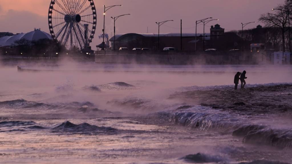 dpatopbilder - Menschen spazieren in Chicago über einen mit Eis bedeckten Strand am Ufer des Michigansees. Foto: Kiichiro Sato/AP/dpa