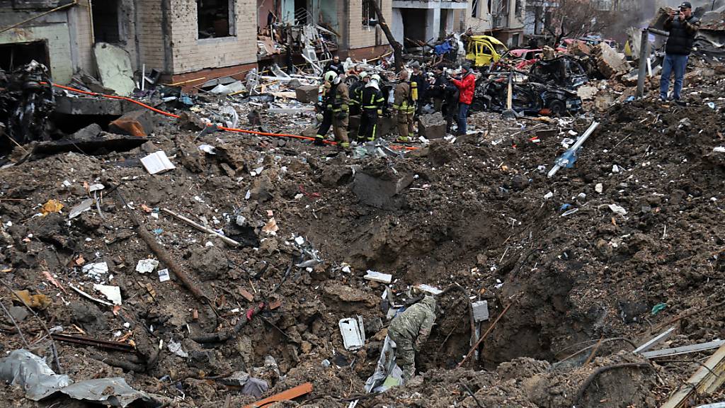 ARCHIV - Rettungskräfte stehen neben einem Krater in der Nähe beschädigter Wohngebäude in Kiew nach einem russischen Raketenangriff. Russland hat nach Angaben der US-Regierung über den Jahreswechsel u.a. auch Raketen aus Nordkorea im Angriffskrieg gegen die Ukraine eingesetzt. Foto: -/Ukrinform/dpa