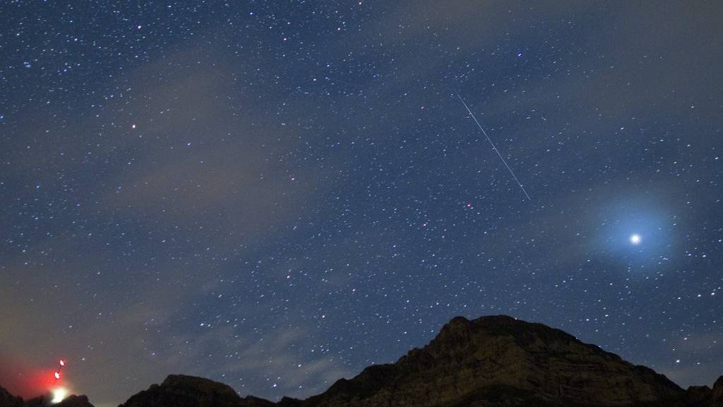 Eine Sternschnuppe fällt vom Nachthimmel über dem Säntis.