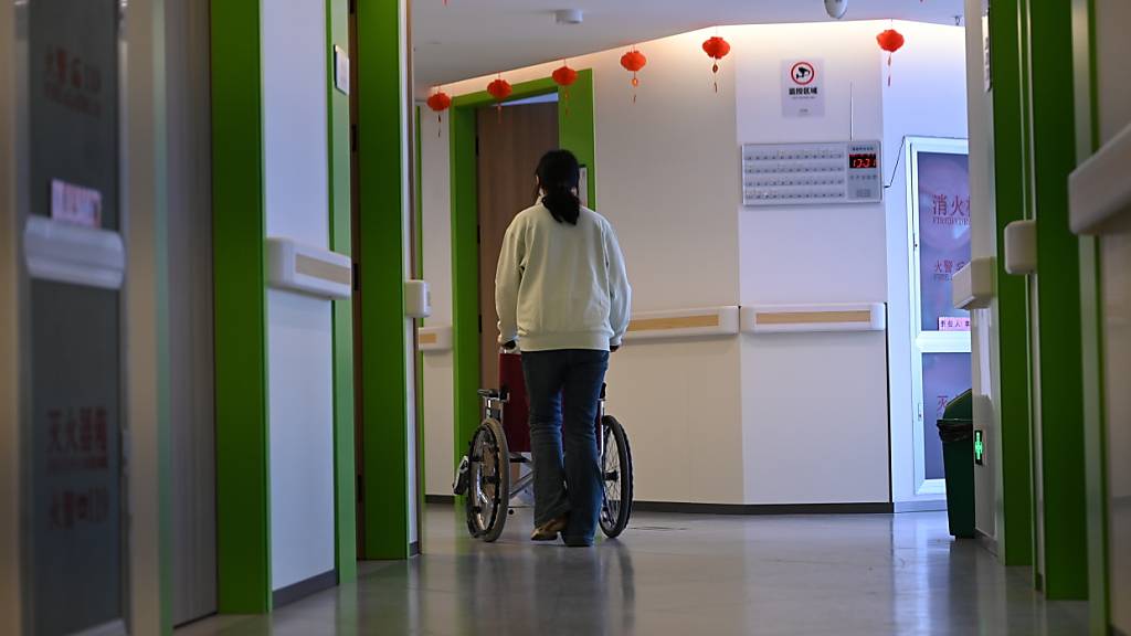 ARCHIV - Eine Altenpflegerin schiebt einen Rollstuhl in einem Flur. In China gibt es landesweit Projekte, in denen ehemalige Schulen oder Kindergärten in Pflegeheime umfunktioniert werden. Foto: Johannes Neudecker/dpa