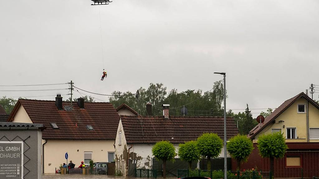 dpatopbilder - Aus einem Polizeihubschrauber wird ein Wasserretter abgeseilt. Nach den ergiebigen Regenfällen der letzten Tage gibt es Hochwasser in der Region. Foto: Stefan Puchner/dpa