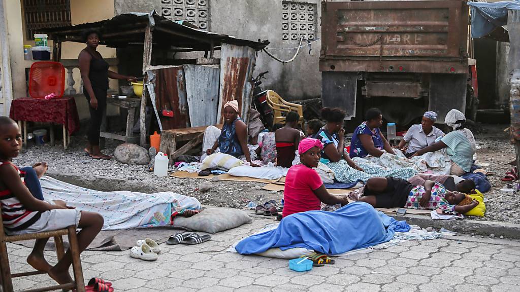 Einheimische, die die Nacht in Schlafsäcken im Freien verbracht haben, wachen am Tag nach einem Erdbeben auf. Das Erdbeben der Stärke 7,2 hat Haiti am 14.08.2021 erschüttert. Foto: Joseph Odelyn/AP/dpa
